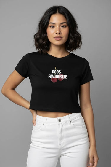 Woman wearing a black graphic crop top with 'GODS FAVOURITE' text and cherries, standing against a gray background