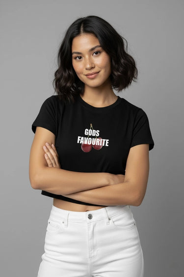 Woman wearing a black graphic crop top with 'GODS FAVOURITE' text and cherries design on a gray background