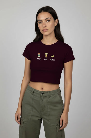Woman wearing a maroon graphic crop top with text and symbols on a plain background