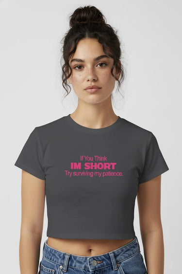 Woman wearing a dark gray graphic crop top with pink text on a white background