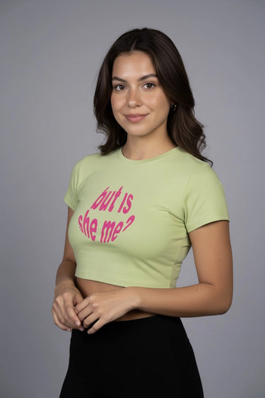 Woman wearing a light green graphic crop top with pink text against a gray background