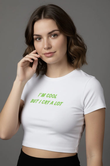 Woman wearing a white graphic crop top with green text on a gray background