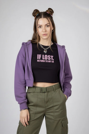 Person wearing a purple hoodie, black shirt with text, that says "If Lost, Return to My Ex" and green pants on a plain background