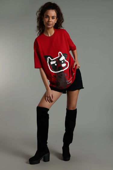 Person wearing a red unisex oversized fool face t-shirt with a graphic design, black shorts, and black knee-high boots on a gray background