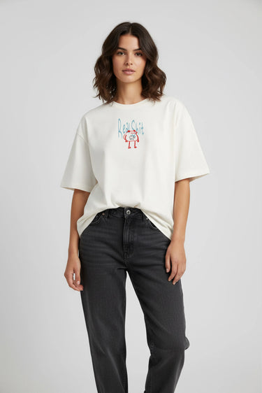 White oversized graphic t-shirt with colorful abstract design on chest, paired with black jeans.