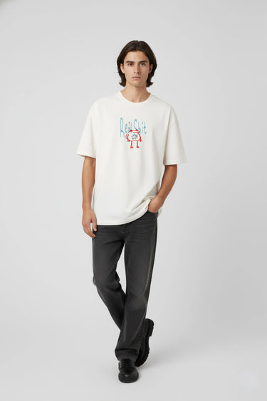 White oversized graphic t-shirt with colorful abstract print, paired with black pants.